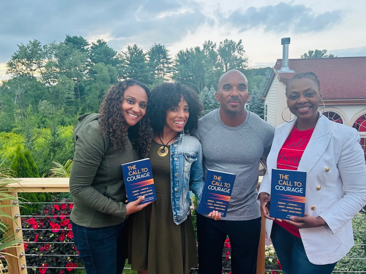 Dr. Brown with three people holding copies of The Call to Courage